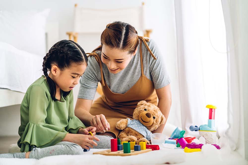 A mother showing her daughter how to use a puzzle board