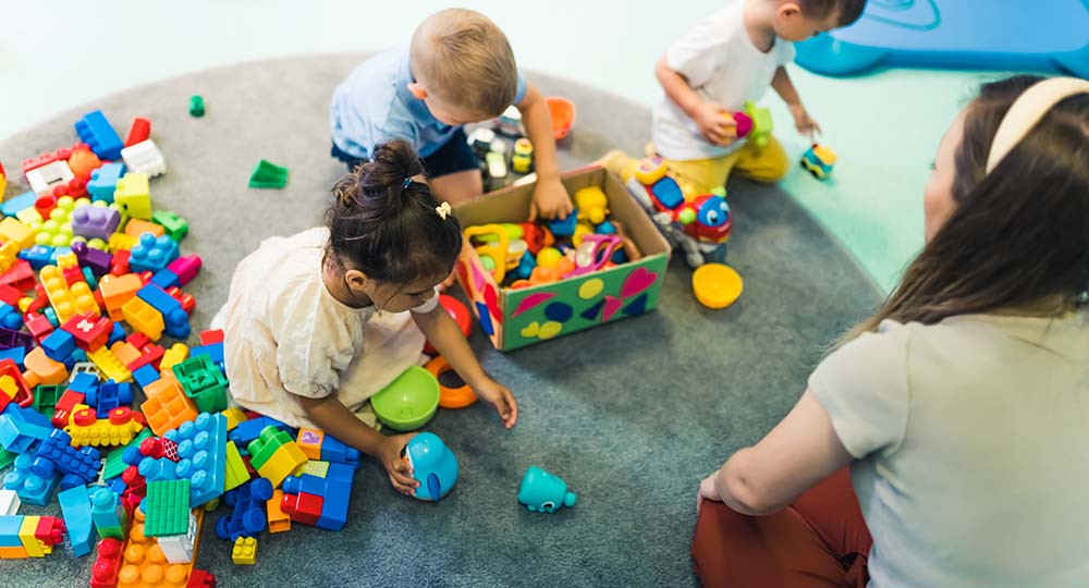 A playgroup with a childcare worker and toddlers playing with toys