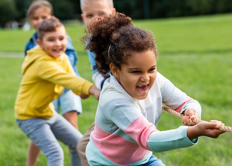 Children playing tug of war in a grassy field